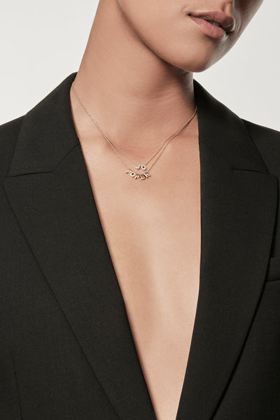 Close-up of a woman wearing a minimalist 18k gold initials “P" "D" "P" "B" "R" necklace and diamond initials "J" "O" charm necklace on a fine chain, styled with a black blazer – personalised alphabet pendant jewellery