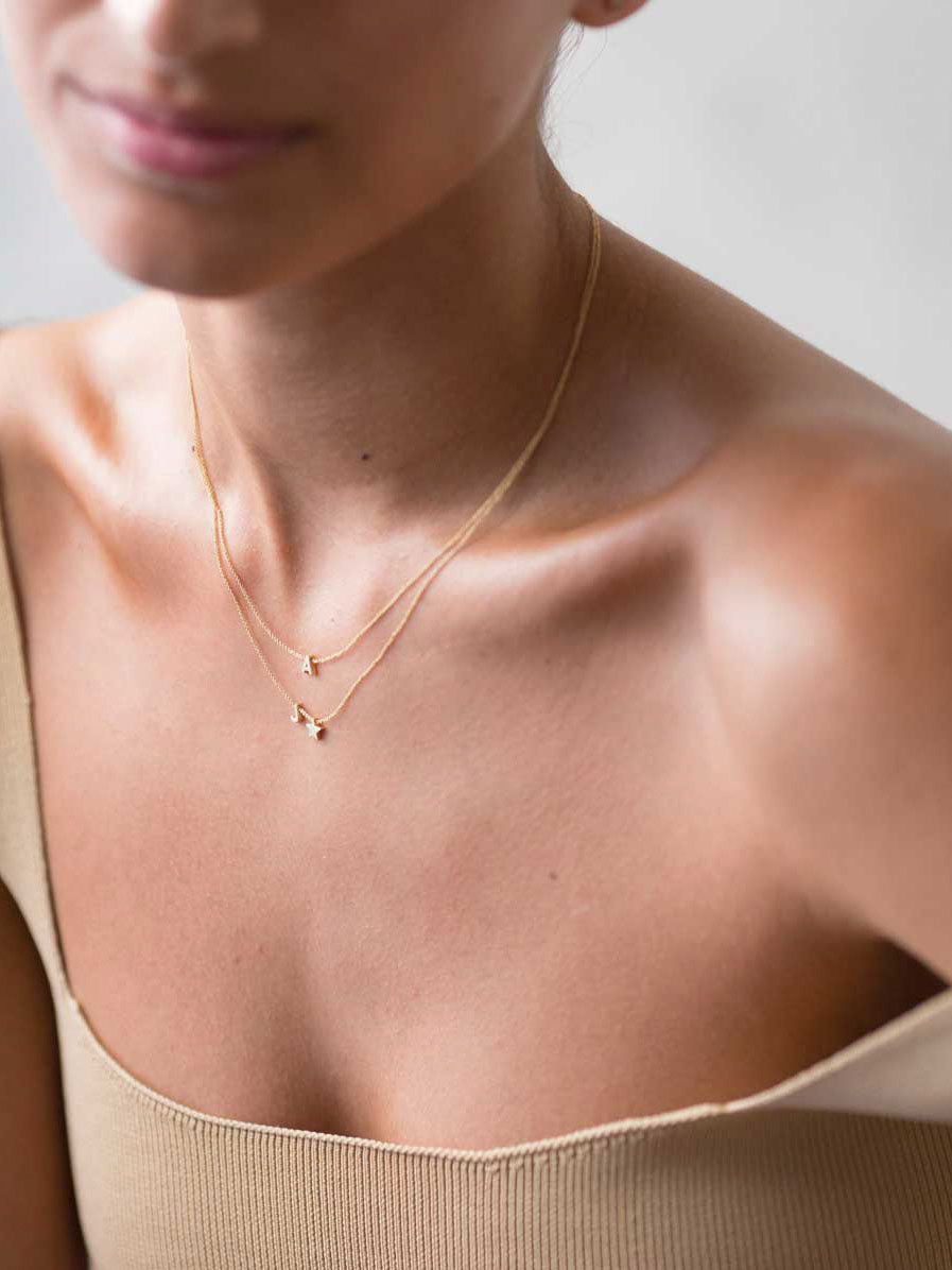 Miniature three-dimensional diamond letters in 18k solid gold, thread onto an adjustable chain.